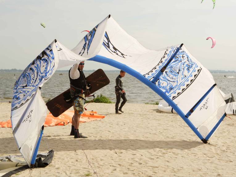 Ein Kitesurfer am Strand, der sein Segel in den Wind hält