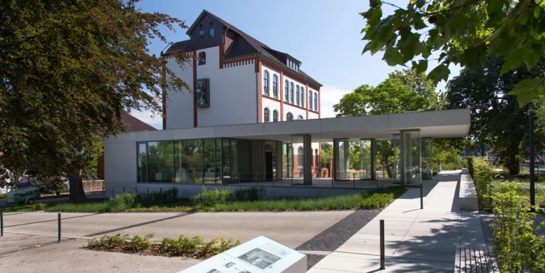 Blick von außen auf ein Gebäude mit gläsernem Foyer.