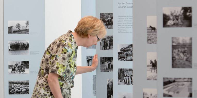 Eine Frau betrachtet Info- und Bildertafeln in einer Ausstellung