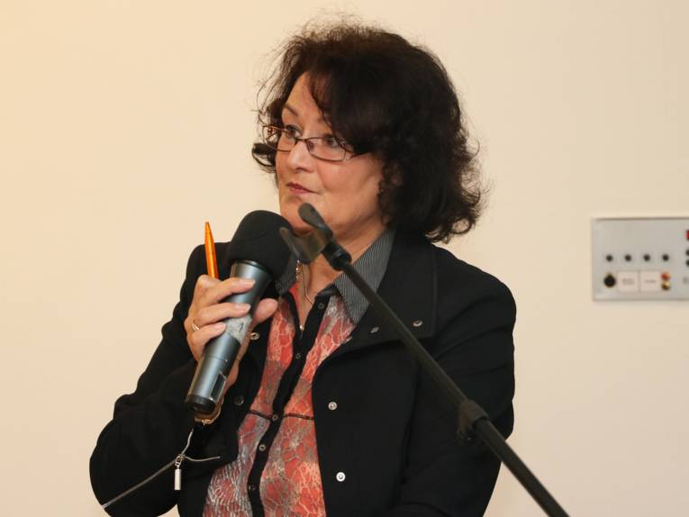 Eine Frau mit Brille spricht in ein Mikrofon.