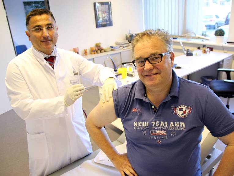 Ein Arzt gibt einem männlichen Patienten eine Spritze.