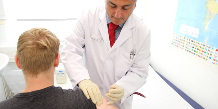 Ein Arzt gibt einem jungen Mann eine Spritze in den Oberarm