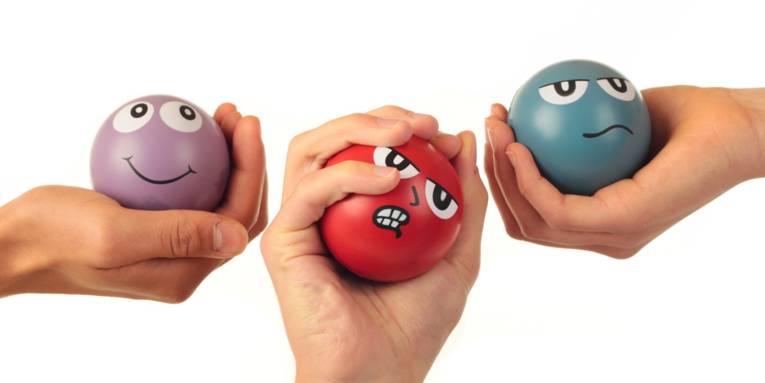 Drei Bälle mit aufgemalten Gesichtern, die die Stimmungslagen Zufrieden, Verärgert und Neutral, zeigen. Jeder Ball wird von einer Hand gehalten