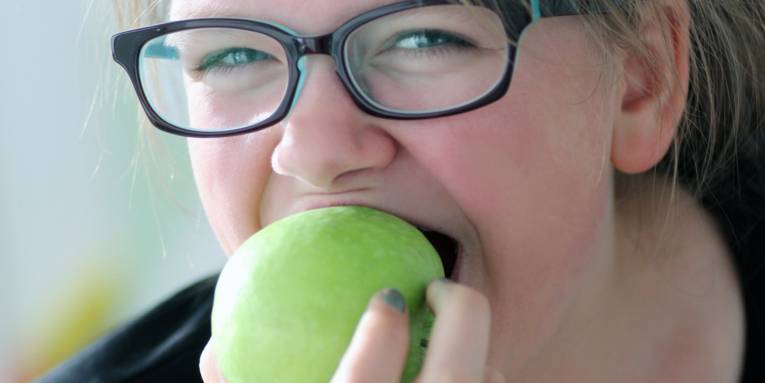 Eine Frau beißt in einen Apfel.