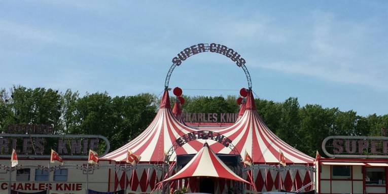 Ein weiß-rotes Zirkuszelt mit überdachtem Eingangsbereich. 