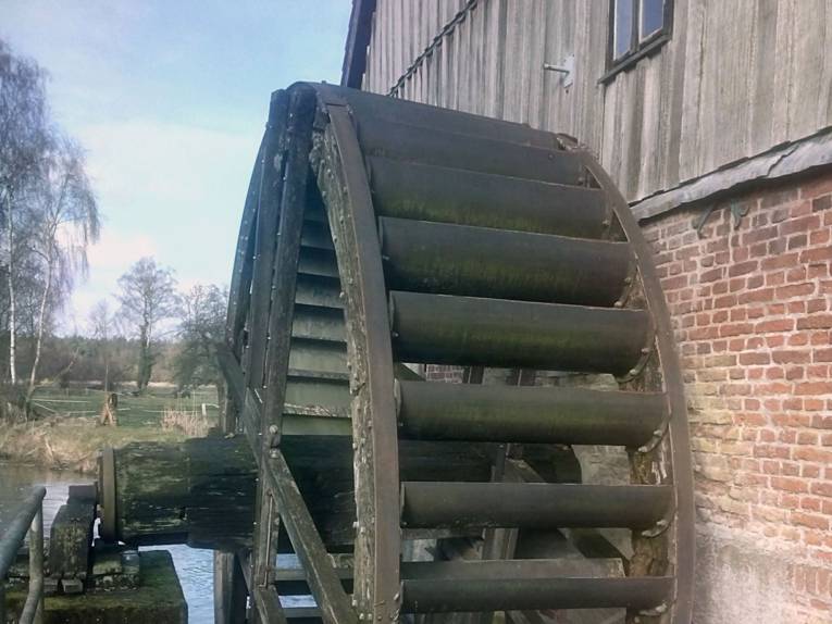 Blick auf eine Wassermühle mit einem großen Eichenrad.