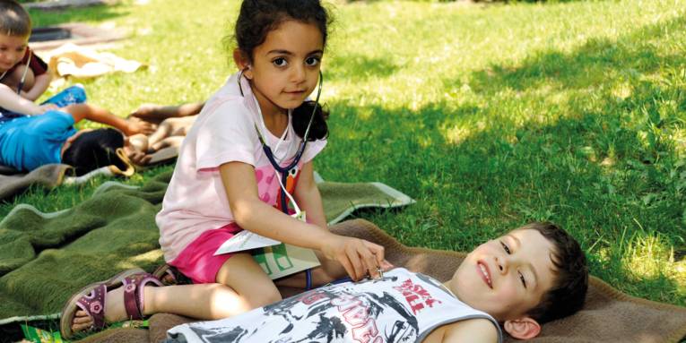 Kinder im Park, die sich gegenseitig mit einem Stethoskop abhören.