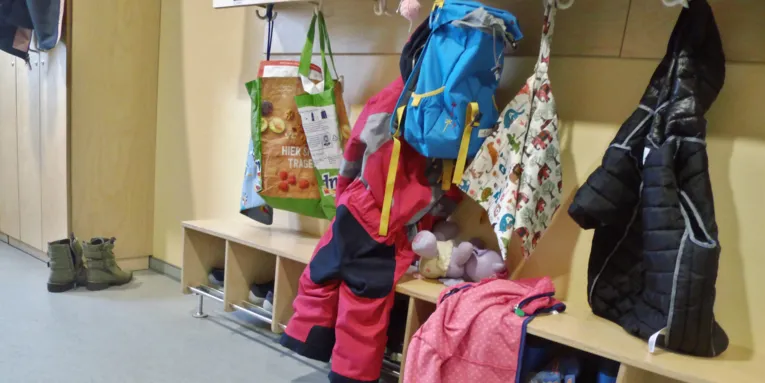 Garderobe mit Rucksäcken, Taschen, Jacken und weiteren Kleidungsstücken.