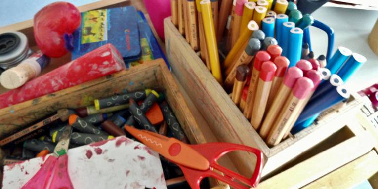Stifte, Scheren und weiteres Material sind in einer kleinen Holzkiste.