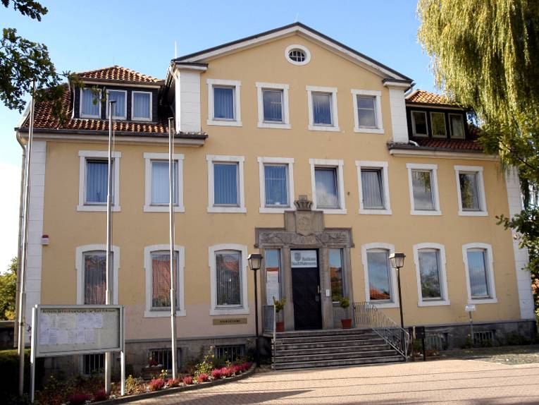 Dreigeschossiger Bau mit gelber Fassade vor blauem Himmel.