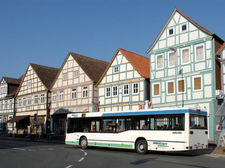 Ein Bus der RegioBus biegt um eine Kurve auf die Marktstraße in Burgdorf ein, im Hintergrund steht eine Reihe alter Fachwerkhäuser dicht an dicht nebeneinander.