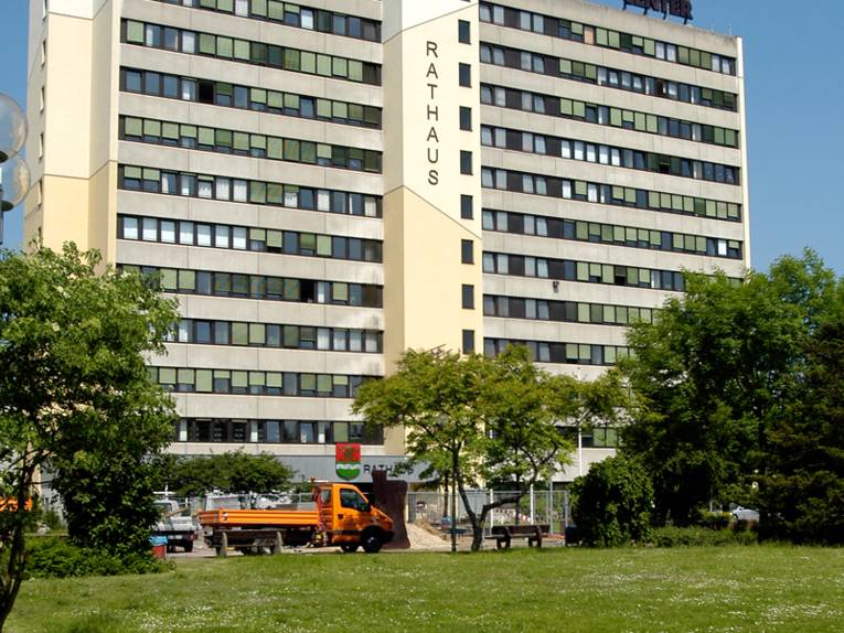 Grünflache, im Hintergrund zwei Hochhäuser vor den ein oranger LKW parkt