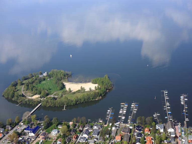 Blick aus einem Flugzeug auf das Ufer des Steinhuder Meeres mit Bootsanlegern und Wald und der Badeinsel.