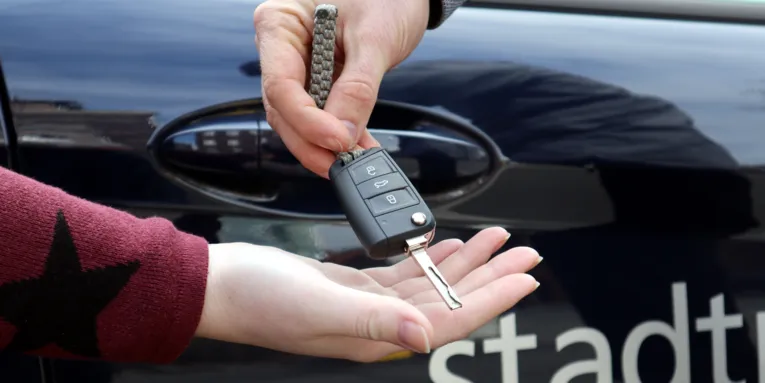 Eine Hand übergibt einen Autoschlüssel in eine andere Hand.