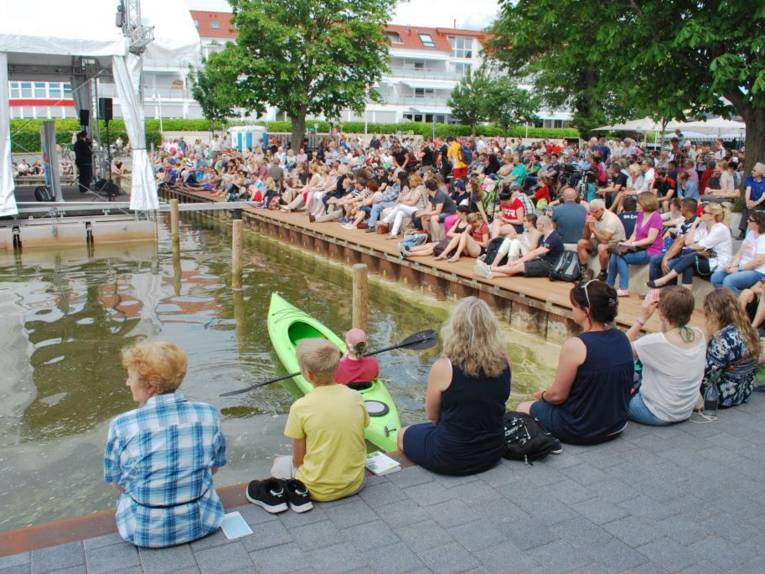 Publikum verfolgt einen Poetry Slam auf der schwimmenden VW-Seebühne.