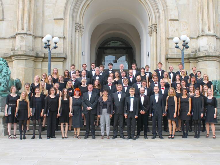 39 Frauen und 27 Männer tragen festliche Kleidung und stehen auf den Stufen zum Hauptgebäude der Leibniz Universität Hannover.