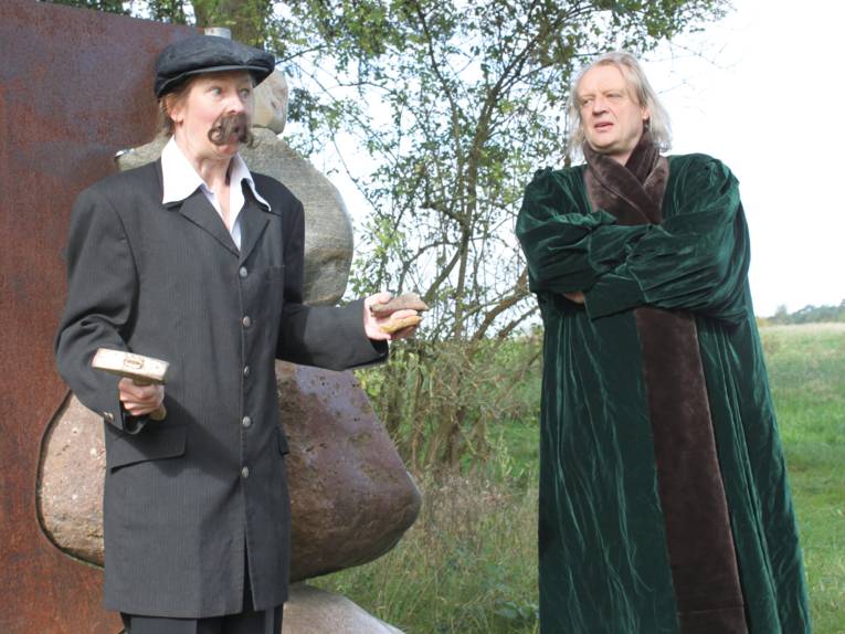 Eine als Mann kostümierte Frau und ein Mann stehen nebeneinander.