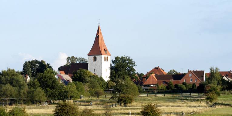 Blick über Wiesen auf den Kirchturm der St. Marienkirche von Isernhagen KB