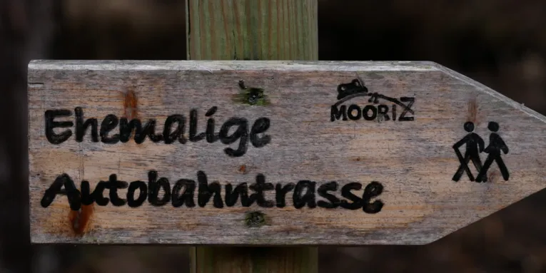 Holzwegweiser mit der Aufschrift "Ehemalige 'Autobahntrasse"