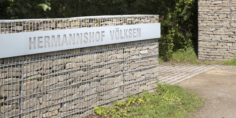 Eingang zu einem Gelände, Schild mit dem Schriftzug "Hermannshof"