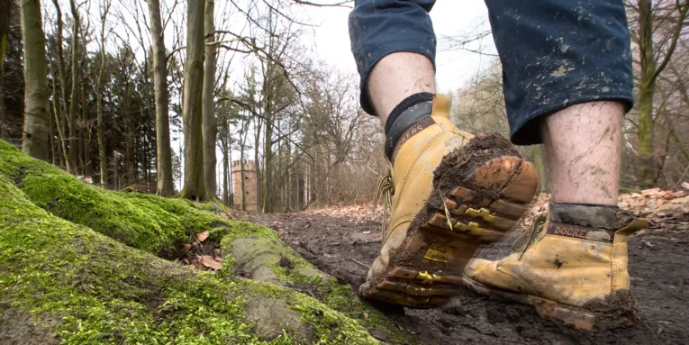 Matschiger Waldweg auf dem jemand mit dreckigen Wanderschuhen geht