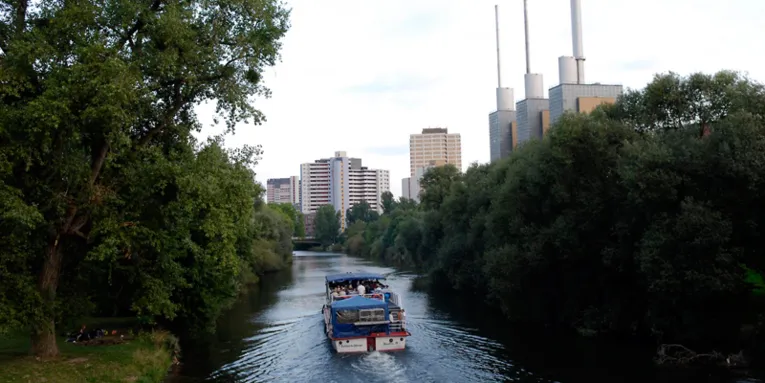 Ein Ausfllugsboot auf der Ihme, im Hintergrund die Stadtwerke und da Ihmezentrum