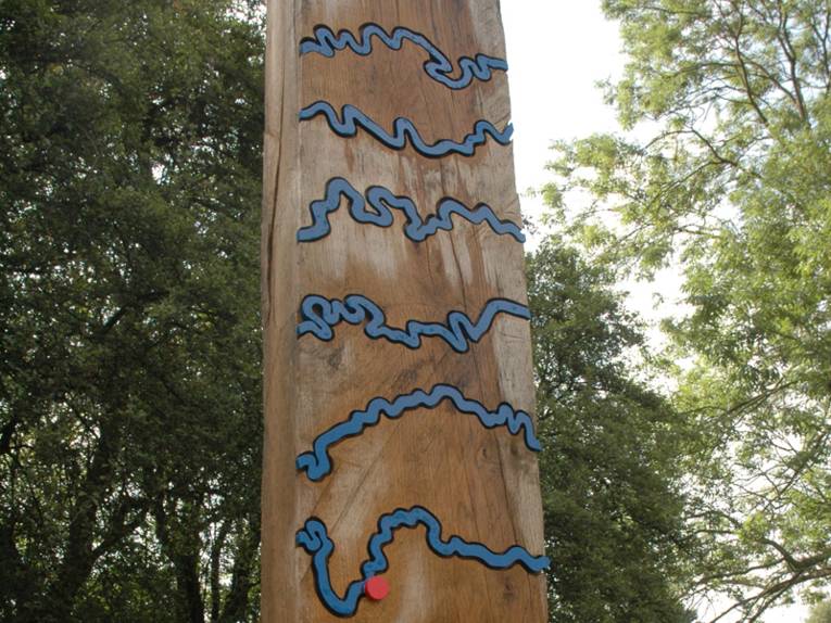 Holzbalken mit blauen Metallwindungen, die einen Flusslauf symbolisieren, und einem roten Ortspunkt