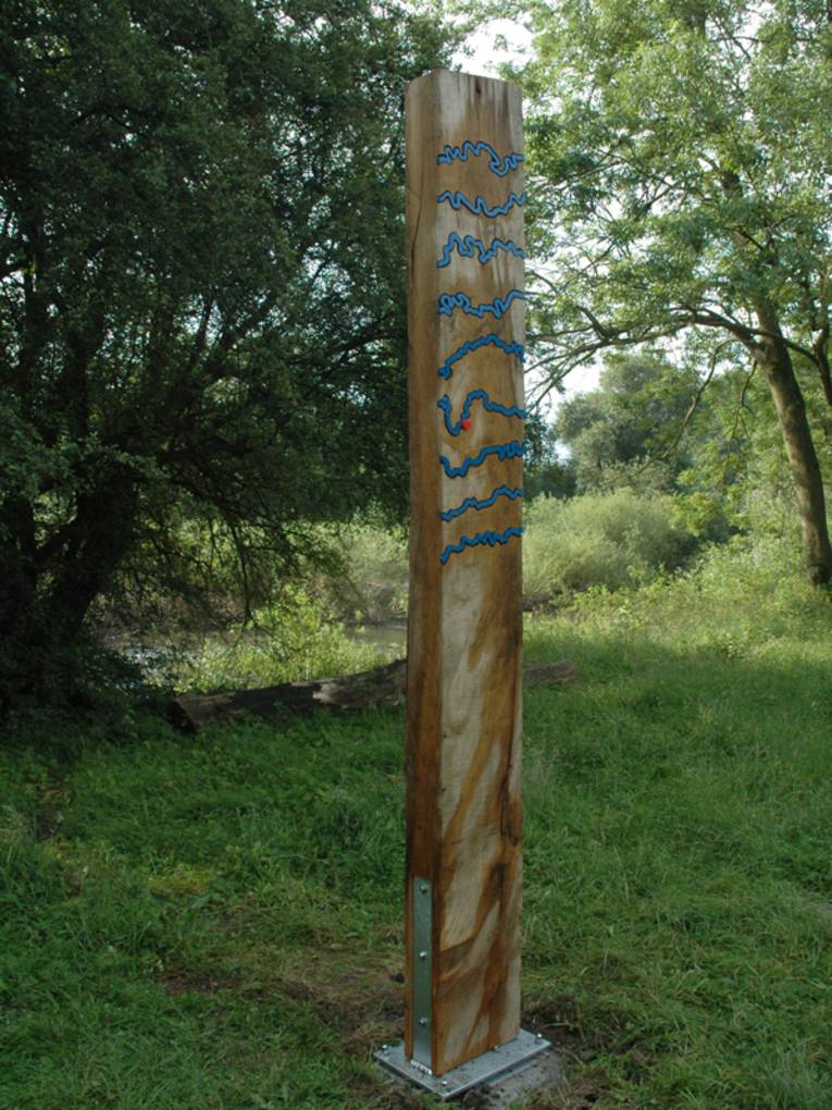 Senkrecht stehender Holzbalken mit blauen Metallwellen und rotem Punkt zur Markierung