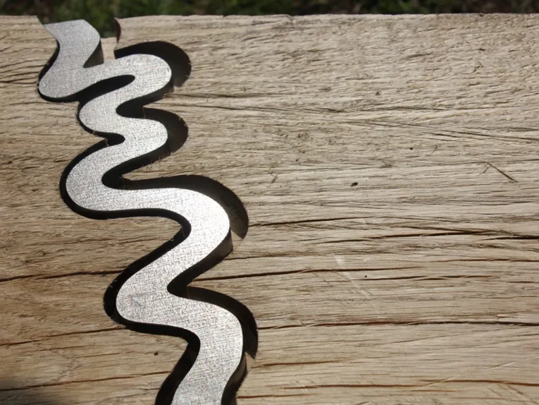 Holzplanke mit eingefrästem Fluss aus Metall