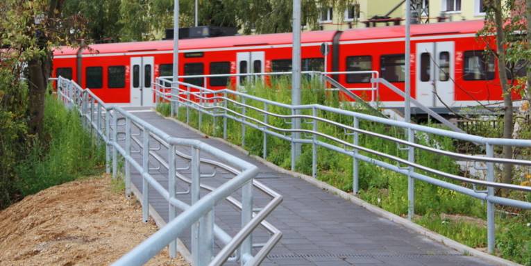 Eine S-Bahn hält am Bahnsteig des S-Bahnhofs Empelde, eine barrierefreie Rampe führt zum Bahnsteig.