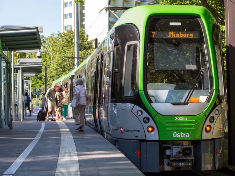 Ein TW3000 hält an einem Hochbahnsteig der Linie 7 in Richtung Misburg, die Stadtbahn lässt Fahrgäste an der Haltestelle ein- und aussteigen.