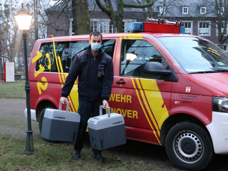 Ein Mann trägt zwei Kühlboxen aus einem Kleintransporter der Feuerwehr