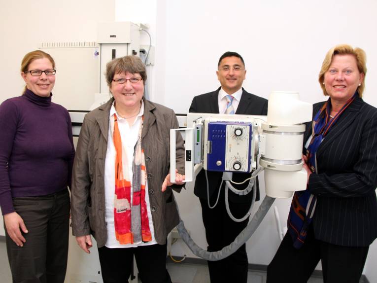 Drei Frauen und ein Mann stehen an einem Röntgengerät zusammen.