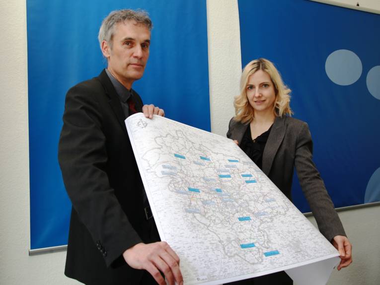 Ein Mann und eine Frau halten eine Landkarte auf der Orte farbig markiert sind