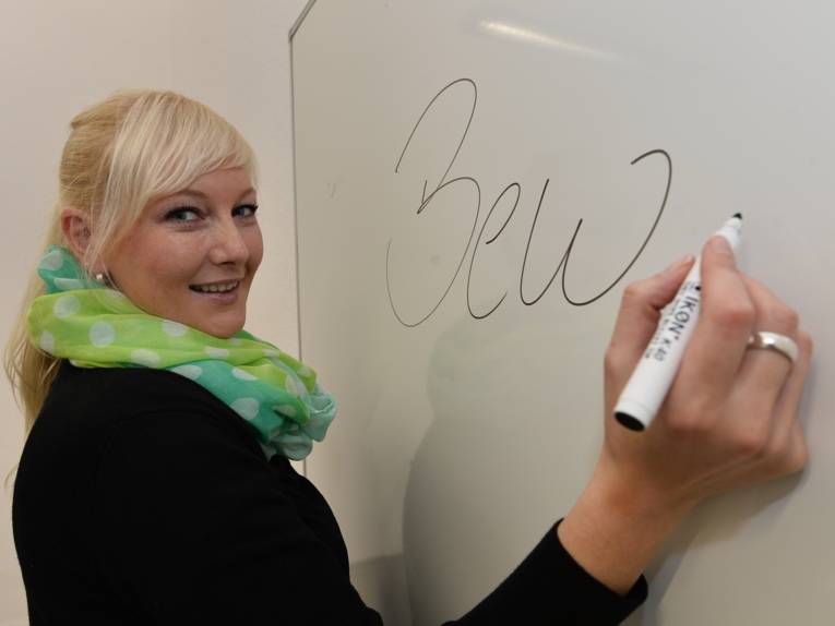 Eine Frau schreibt auf einem Whiteboard.
