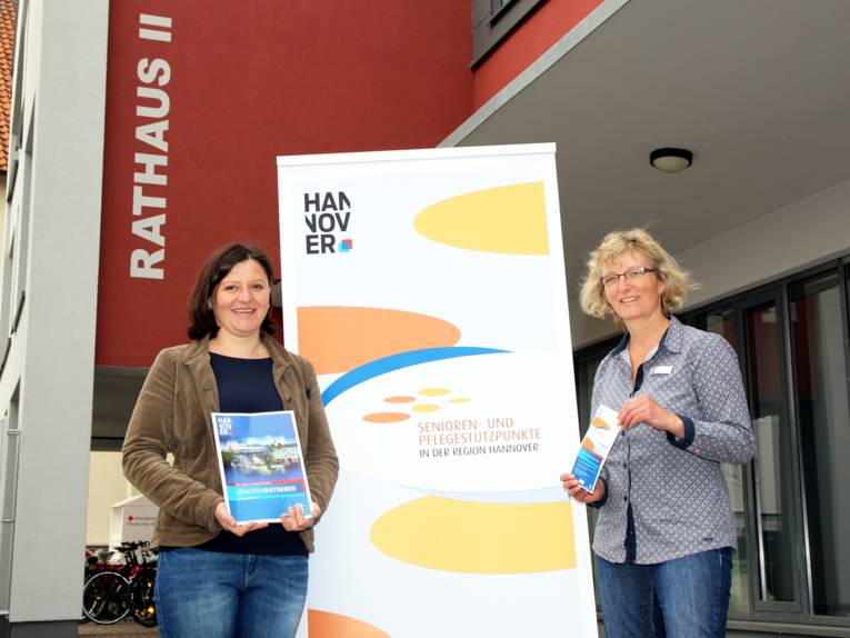 Zwei Frauen stehen vor dem Rathaus II in Barsinghausen und präsentieren Informationsmaterial.