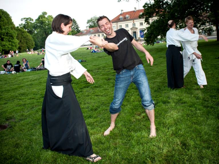 Zwei mal zwei Kampfsportpartner stehen sich gegenüber und trainieren auf einer Rasenfläche.