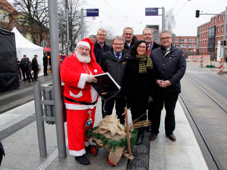 Weihnachtsmann mit fünf Männern und einer Frau auf einem Bahnsteig