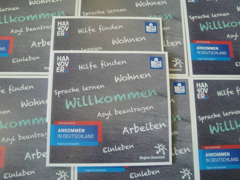 Exemplare der Broschüre "Ankommen in Deutschland – Fragen und Antworten" liegen aufeinander.