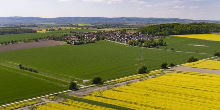Luftbild der Ortschaft Göxe, im Hintergrund Windkraftanlagen und der Deister