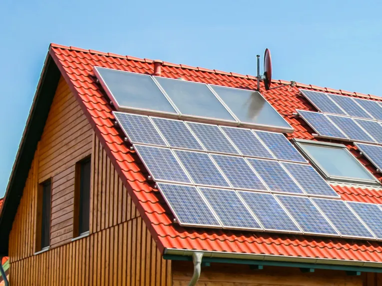 Rotes Ziegeldach eines Hauses auf dem diverse Solaranlagen montiert sind