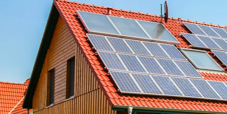 Rotes Ziegeldach eines Hauses auf dem diverse Solaranlagen montiert sind