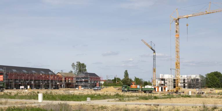 Gebäude im Rohbau, Kran und LKW