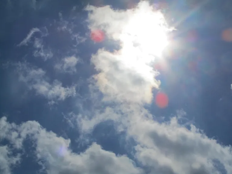 Blick in den Himmel. Vor die Sonne haben sich ein paar weiße Wolken geschoben.