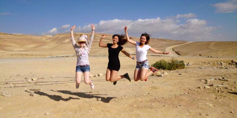 Drei Mädchen sind in einer Wüste und springen in die Luft.