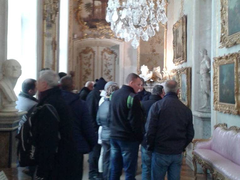 Delegation in Schloss Sanssouci, von der Decke hängt ein Kronleuchter.
