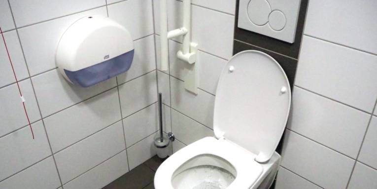 WC mit Haltegriffen, die Menschen mit Behinderungen den Toilettengang erleichtert.