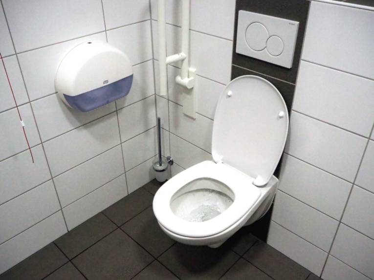 WC mit Haltegriffen, die Menschen mit Behinderungen den Toilettengang erleichtert.