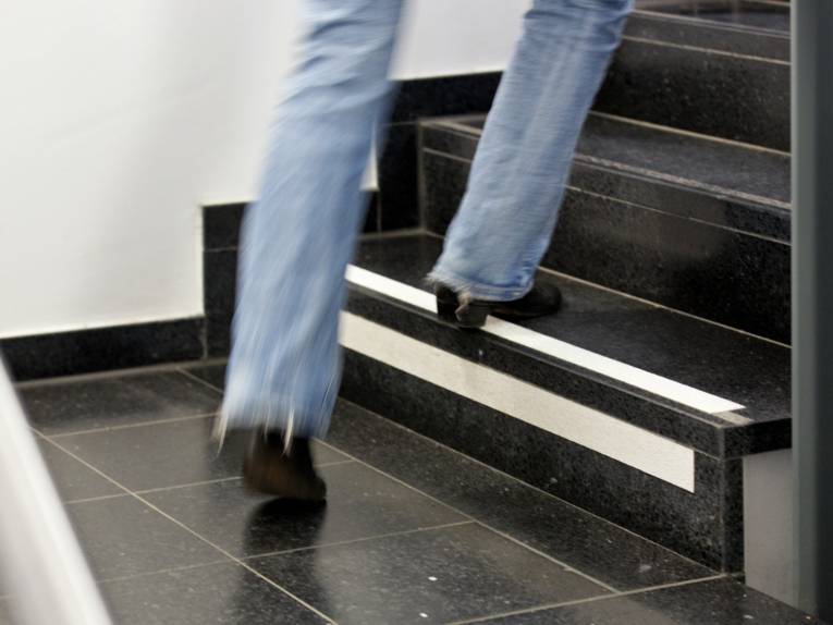 Blick auf die Füße einer Person, die eine Treppe hinauf steigt.