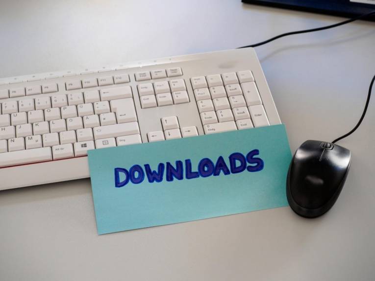 Auf einer Tastatur liegt eine Karteikarte mit der Aufschrift "Download", daneben ist ein Computermaus zu sehen.
